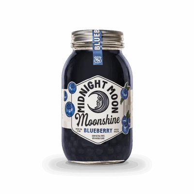 A clear mason jar of Midnight Moon Blueberry Moonshine by Midnight Moon Moonshine has a crescent moon and blueberries on the label, a sealed silver lid, and a small blue tag. The dark blue moonshine is visible inside.