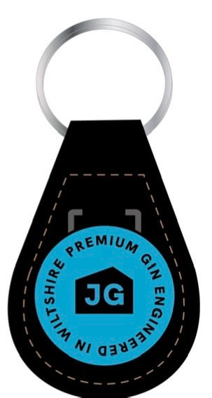 The James Gin The Tupac 2 Bottle Set W/ Souvenir Gift Key Chain by James Gin US includes a black leather keychain with brown stitching and a blue emblem reading &
