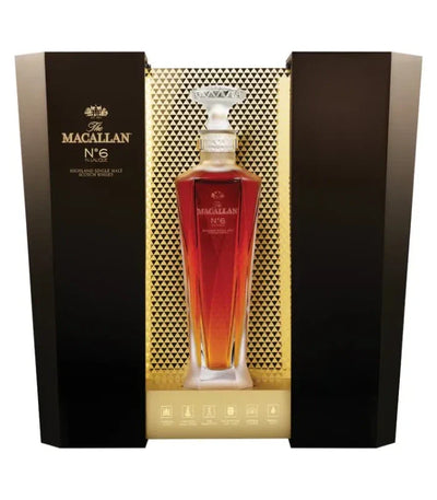 A bottle of The Macallan No. 6 Lalique Single Malt Scotch Whiskey by The Macallan, presented in a luxury crystal decanter and displayed in an elegant black and gold box with geometric patterns.