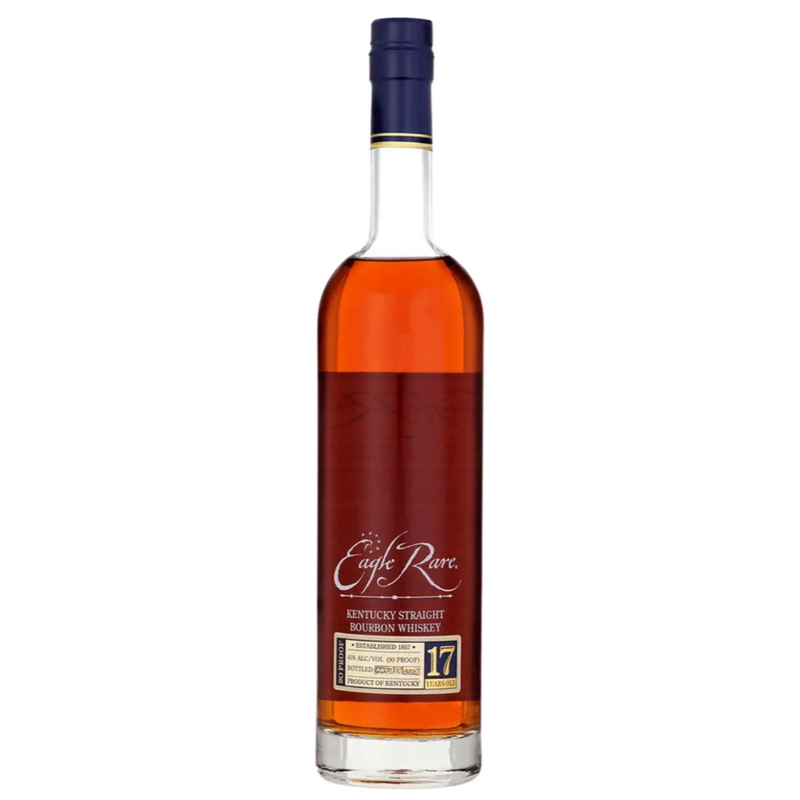 A bottle of Eagle Rare 17 Year Old Bourbon Whiskey 2025 Release from Eagle Rare, featuring a tall clear glass body, navy blue cap, and gold and white label, filled with dark amber Kentucky straight bourbon.